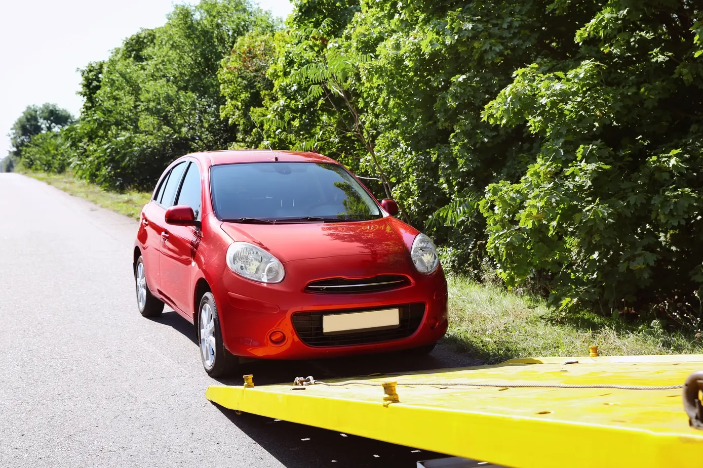 Roter Kleinwagen wird über die Rampe auf die Pritsche eines Abschleppwagens gezogen